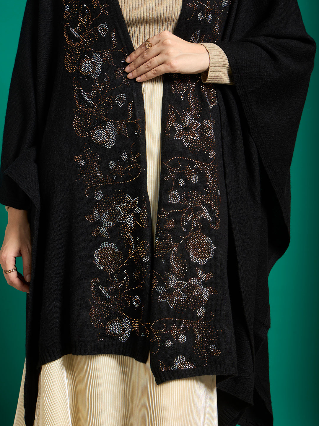 Close-up of silver, bronze and copper crystal floral motifs on a black ribbed knit cape front