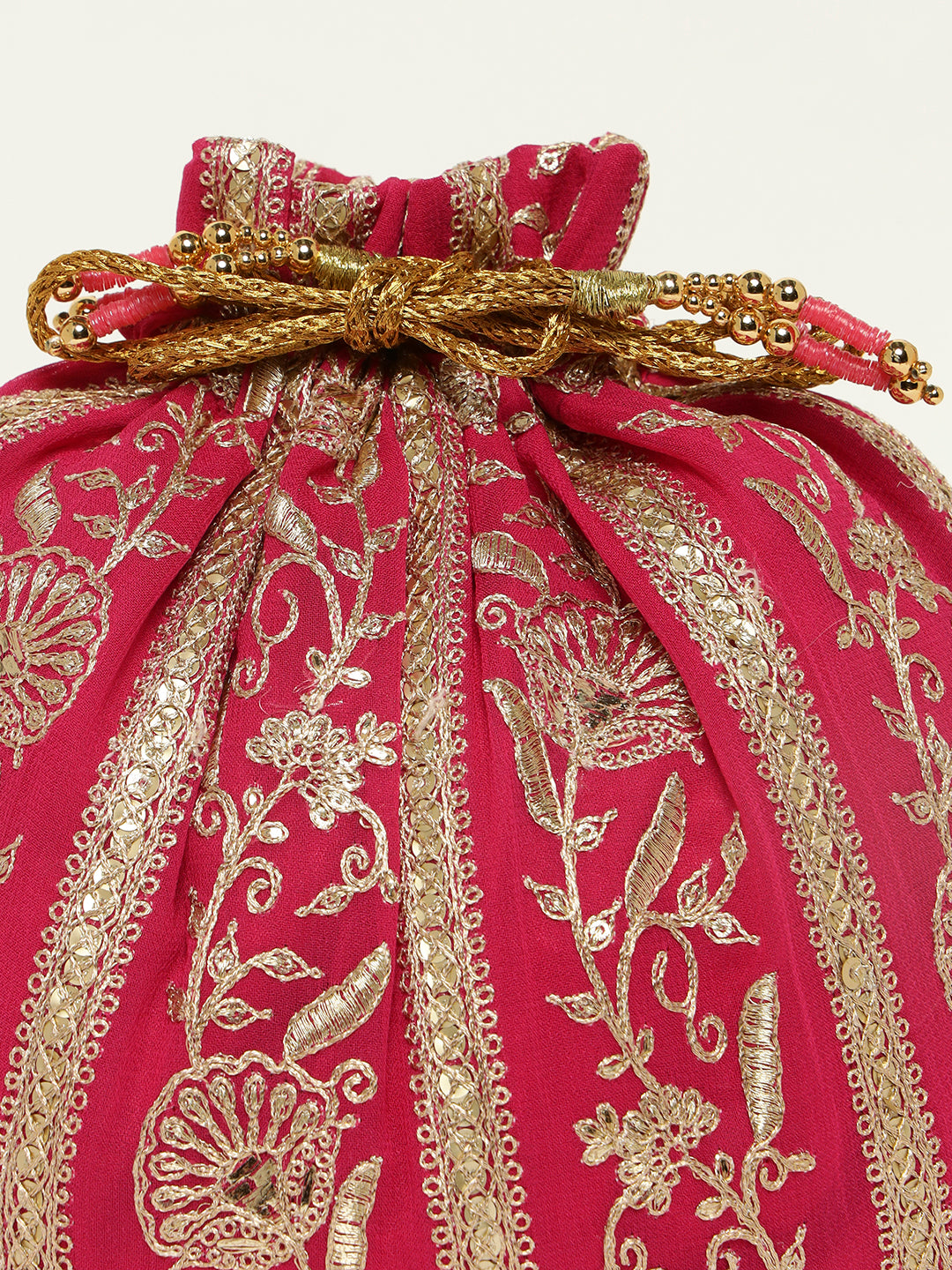 Close-up of golden embroidery on vibrant pink potli