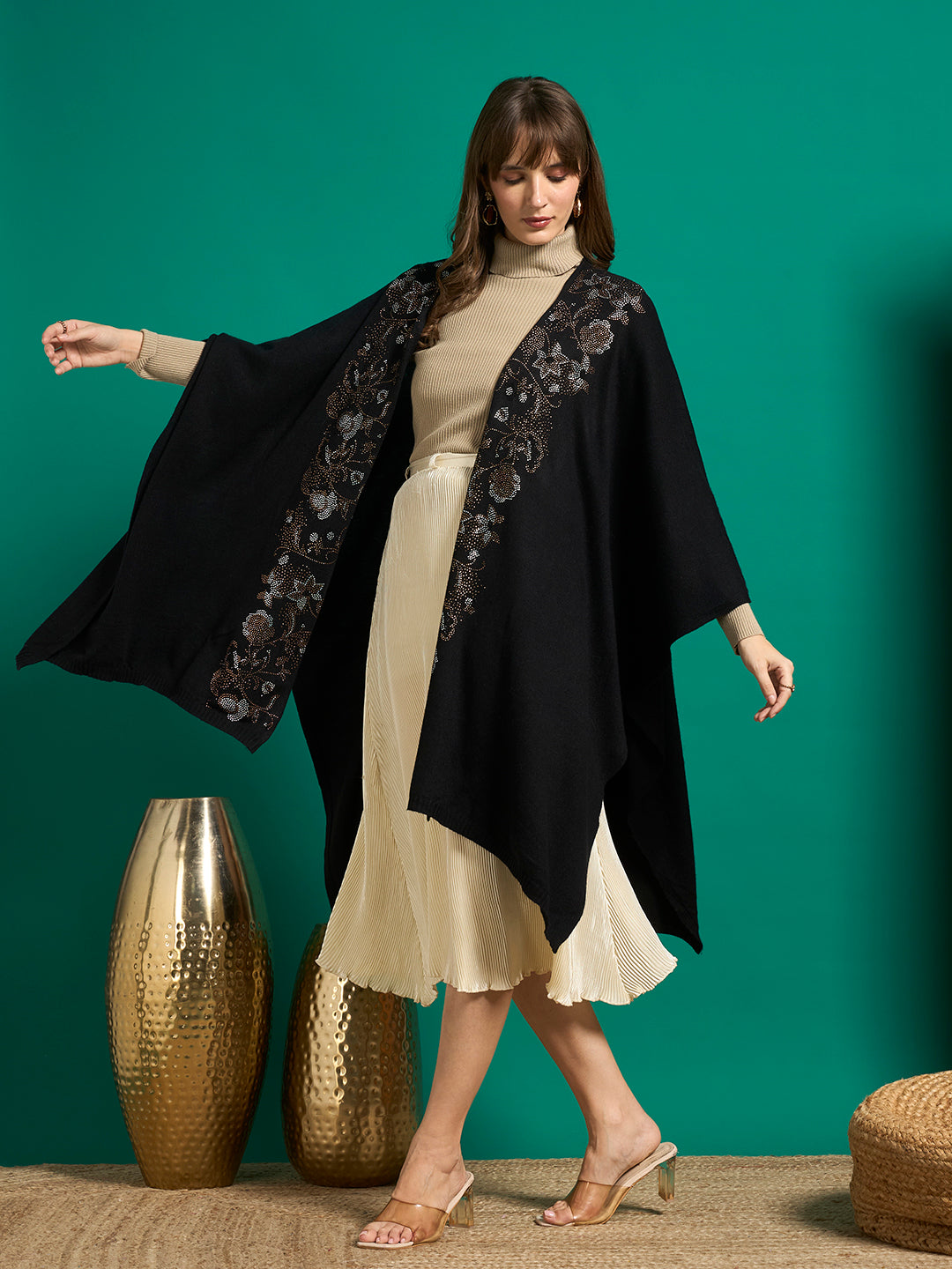 Model in motion with arms out, showing the wide drape of a black cape with crystal floral borders