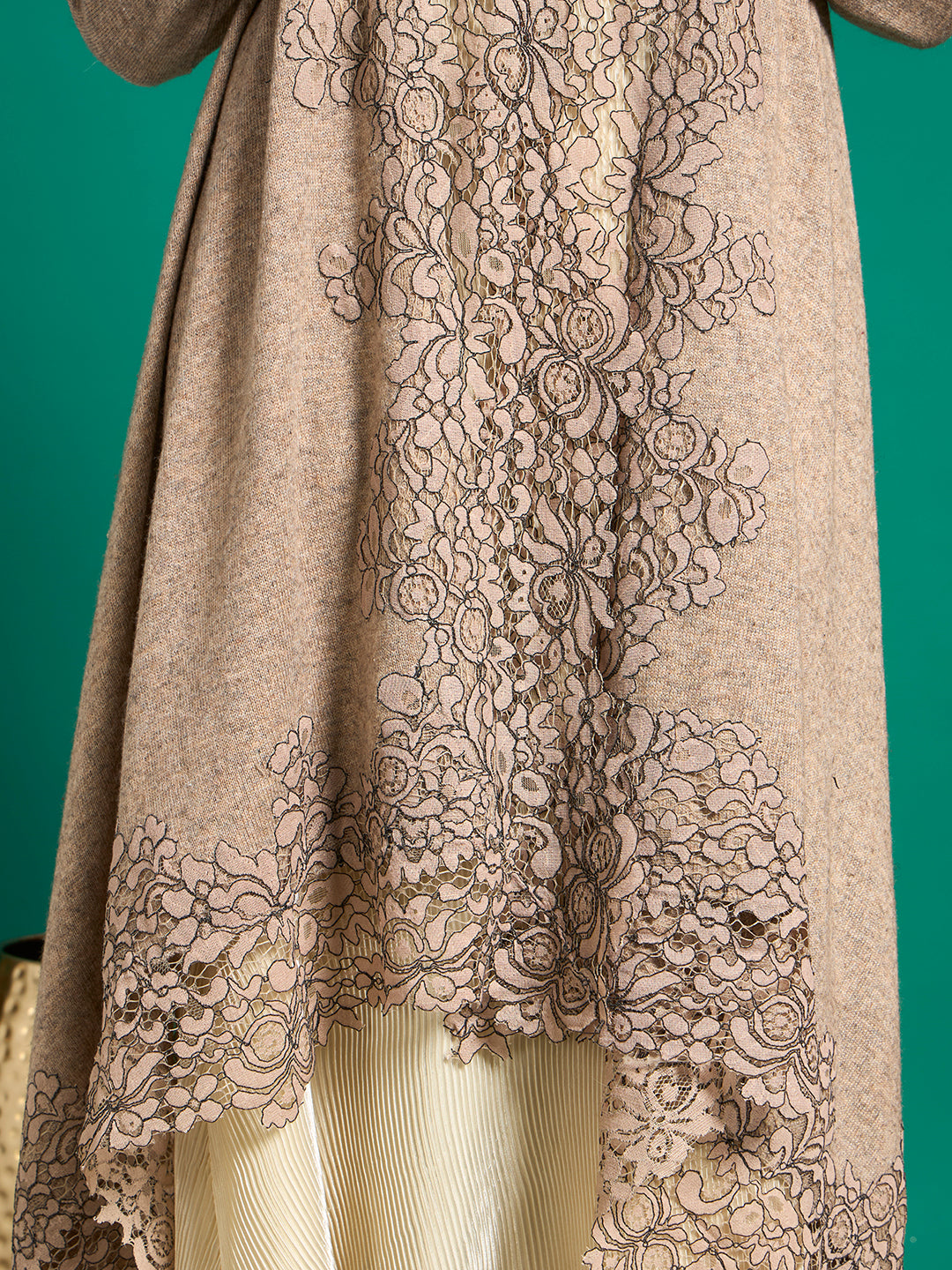 Close-up of taupe corded floral lace with dark outline stitching and scalloped edge on heathered knit