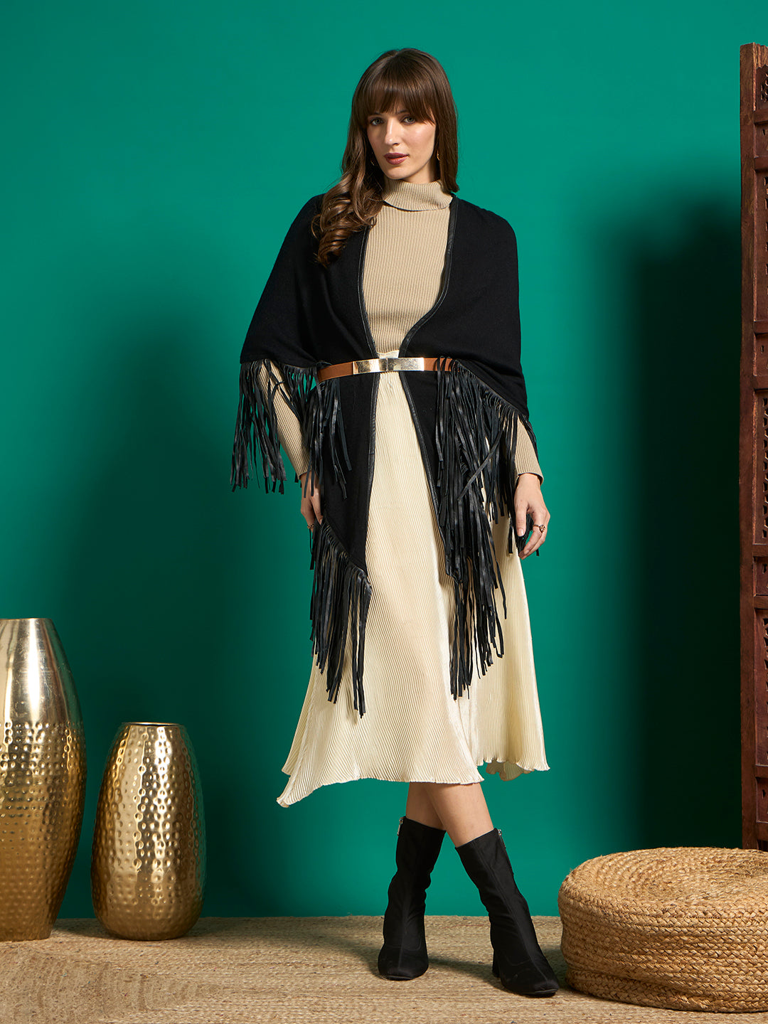 Model in black fringe shawl belted over beige turtleneck and cream pleated midi skirt
