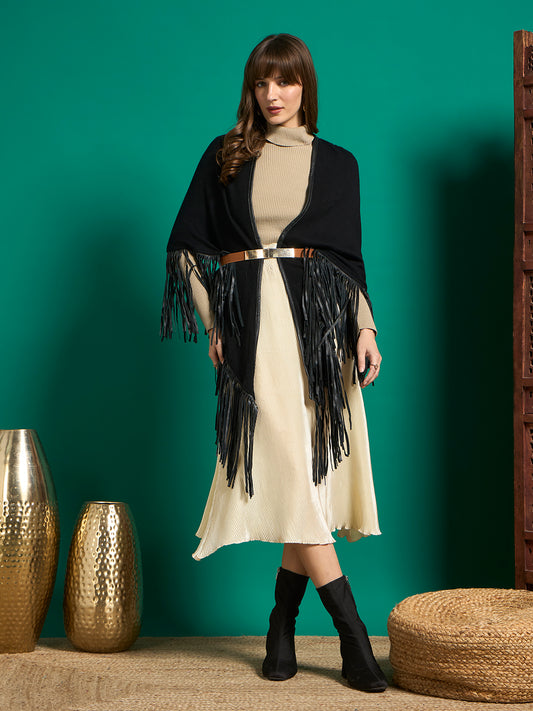 Model in black fringe shawl belted over beige turtleneck and cream pleated midi skirt