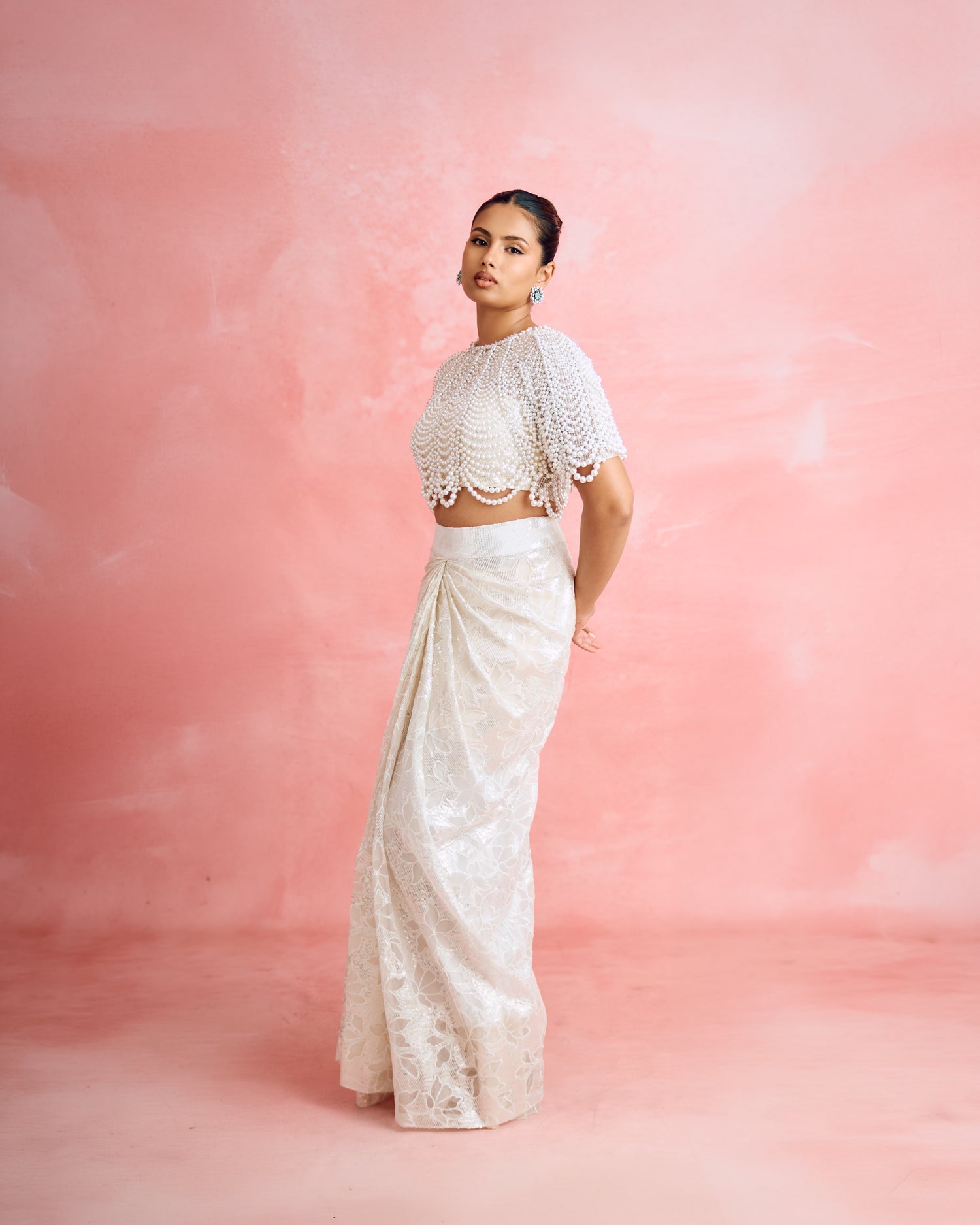 Aashna Hegde wearing Modarta emerald and pearl cluster stud earrings with a pearl-draped top and ivory draped skirt