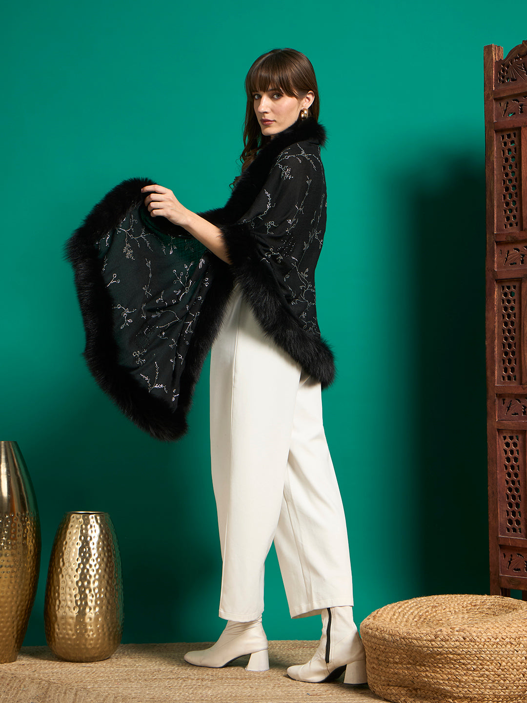 Side view of model holding out black faux fur-edged shawl to show its drape and crystal vine design