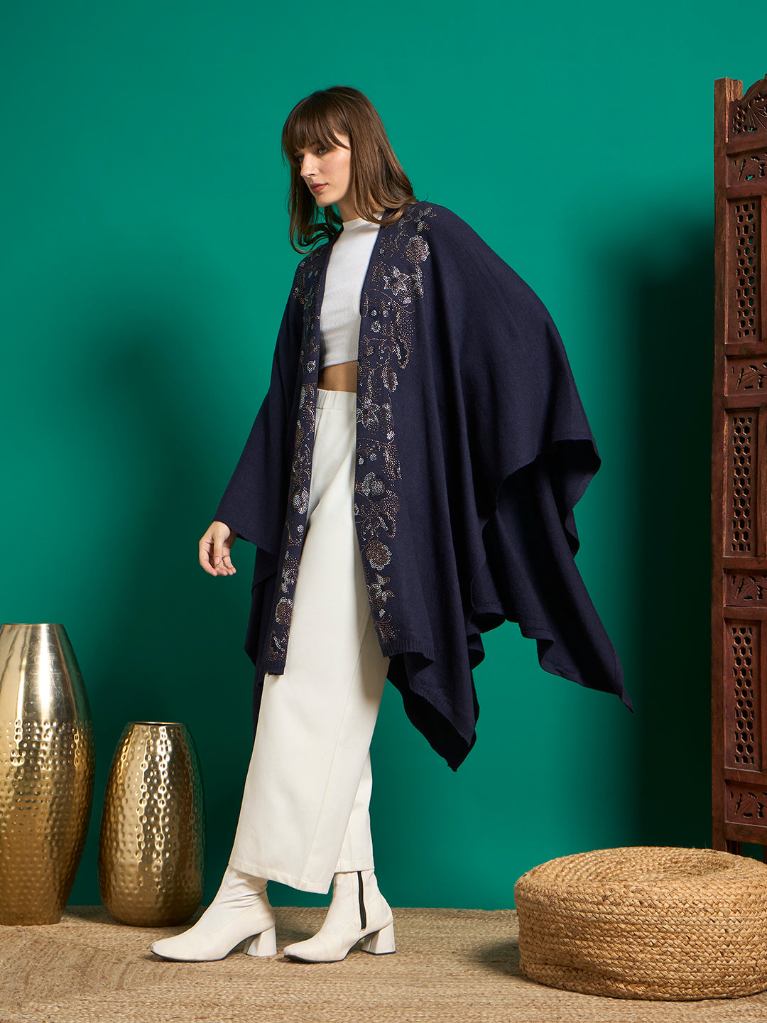 Side view of navy knit cape showing draped asymmetric hem and embellished floral front border