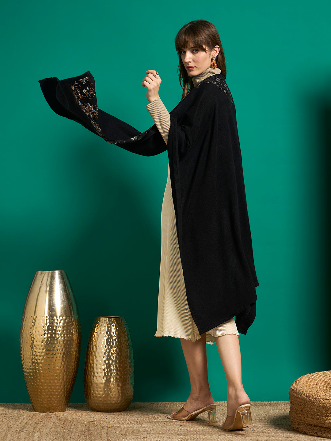 Back view of a black knit cape draped over the shoulders, with crystal floral detailing on the front edge
