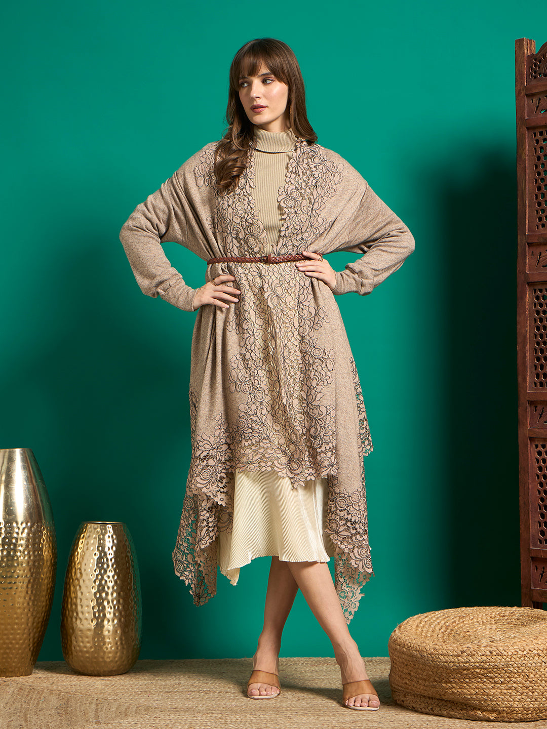 Taupe lace-trimmed cape styled with a brown braided belt over a beige turtleneck and cream midi skirt