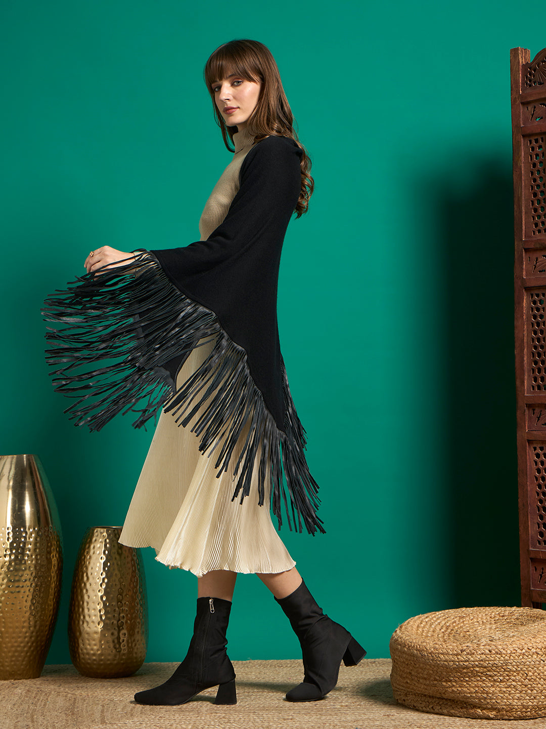Side profile of black knit shawl with long fringe swaying from raised arm
