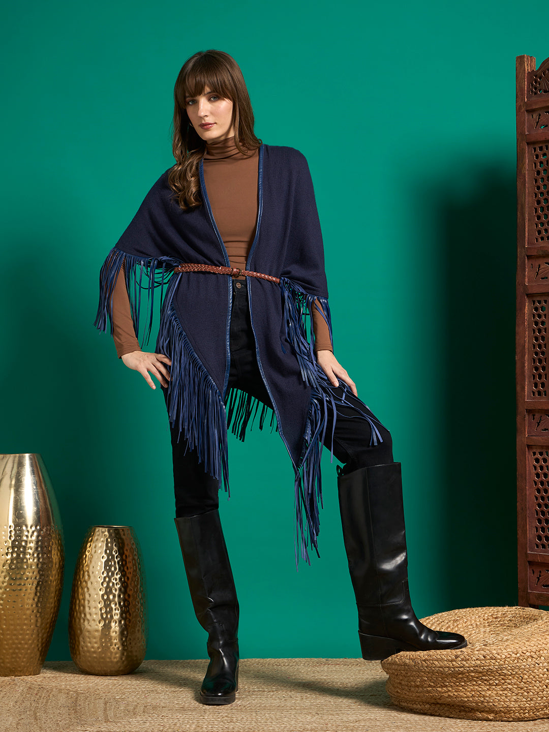 Navy fringe shawl belted at the waist with a braided brown belt over a brown turtleneck and black boots
