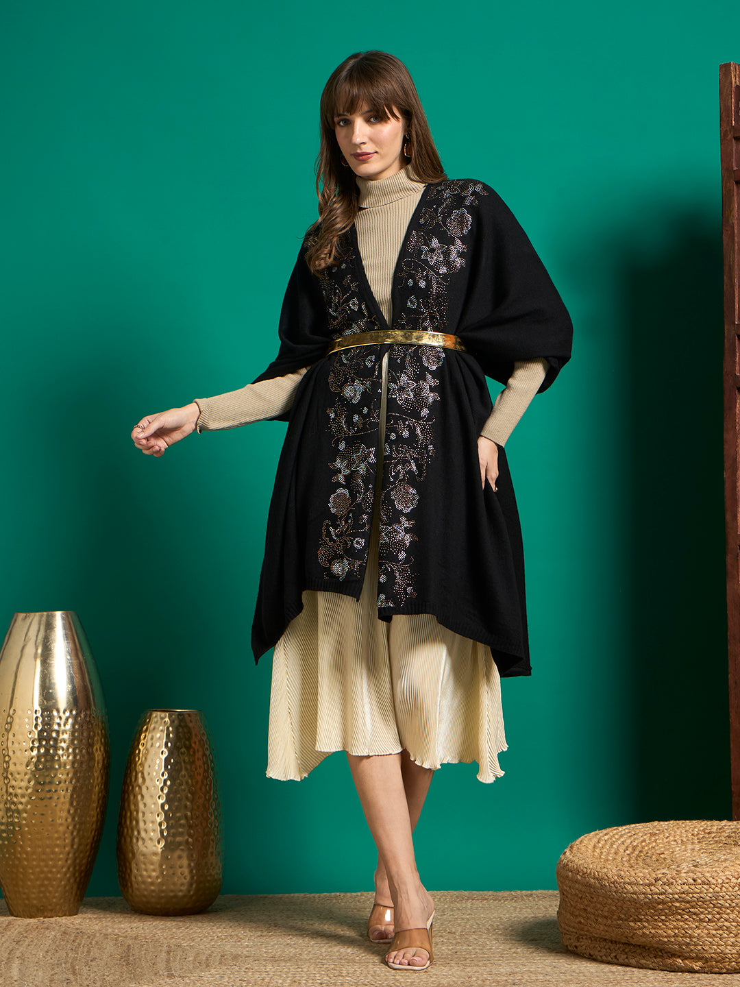 Black crystal floral embellished cape styled with a gold metallic belt over a cream midi skirt