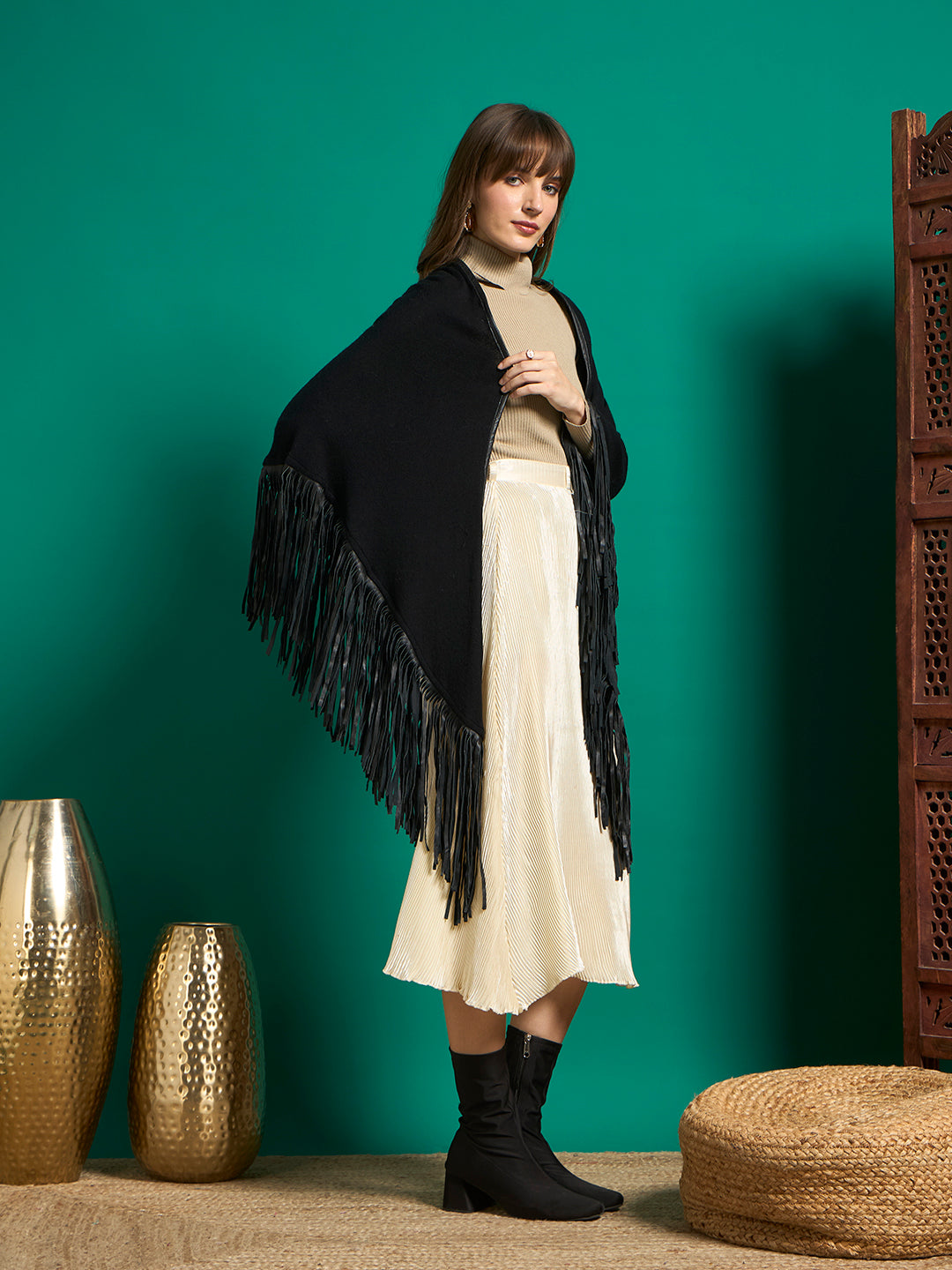 Side view of black fringe shawl draped over shoulders, worn with cream midi skirt and black boots