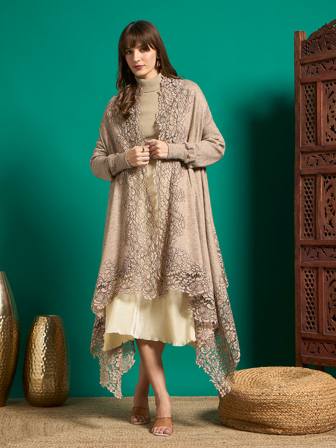 Model in taupe open-front cape with scalloped floral lace front panels and asymmetric hem over cream pleated skirt