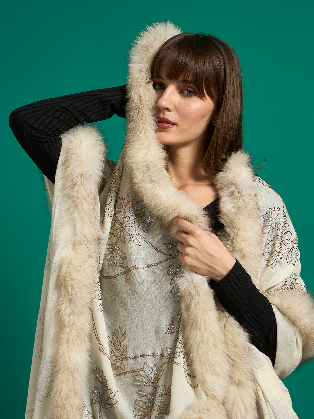 Close-up of ivory shawl draped around shoulders with faux fur trim framing the face and floral studwork