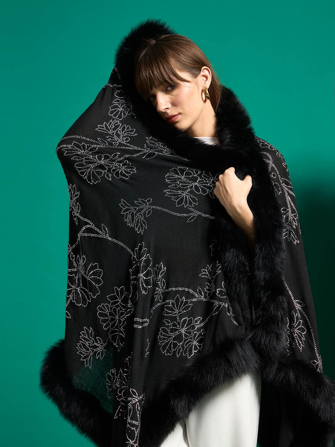 Close view of black shawl with silver crystal flowers and plush black faux fur trim wrapped around shoulders