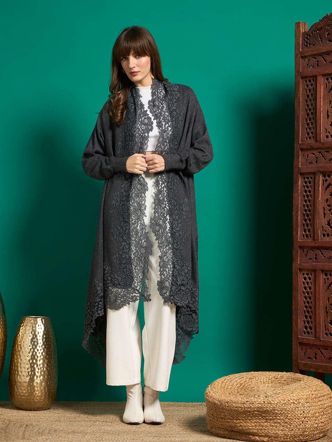Charcoal grey open-front cape with floral lace trim along the front edges and asymmetric hem, worn over white outfit