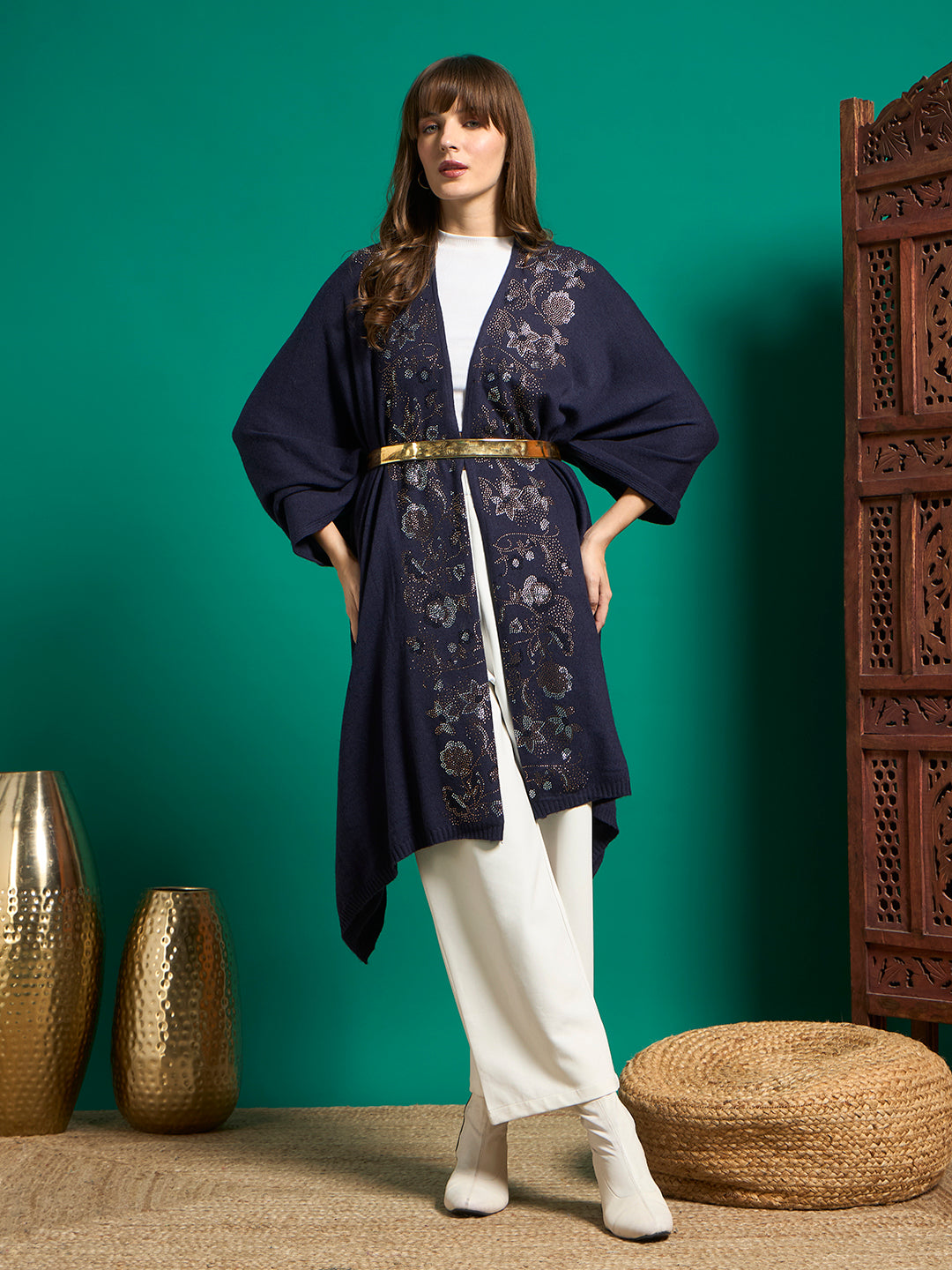 Navy floral embellished cape styled with gold waist belt over white turtleneck and wide-leg trousers